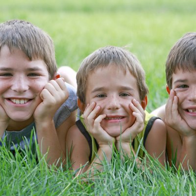 Stock image of three brothers lying next to each other in long grass